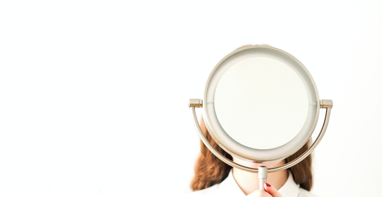 Woman holds mirror in front of face